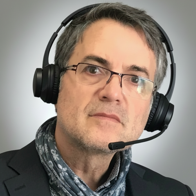 Mann mit Brille und Headset, trägt einen Schal und einen Anzug.